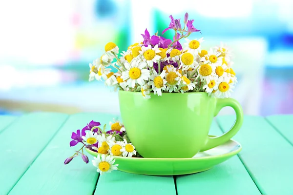 Bouquet of chamomile flowers in cup, on bright background — Stock Photo, Image