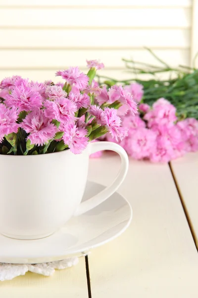 Many small pink cloves in cup on wooden background — Stock Photo, Image