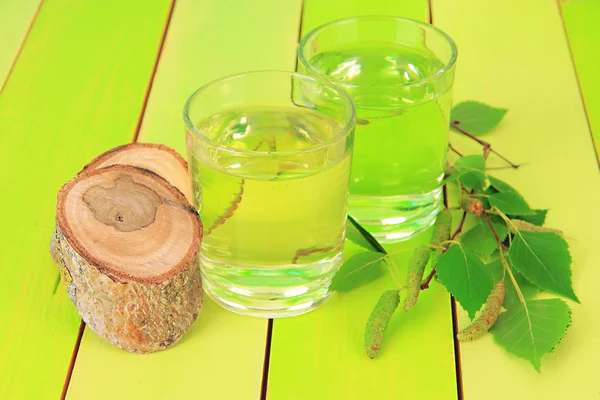 Glasses of birch sap on green wooden table — Stock Photo, Image