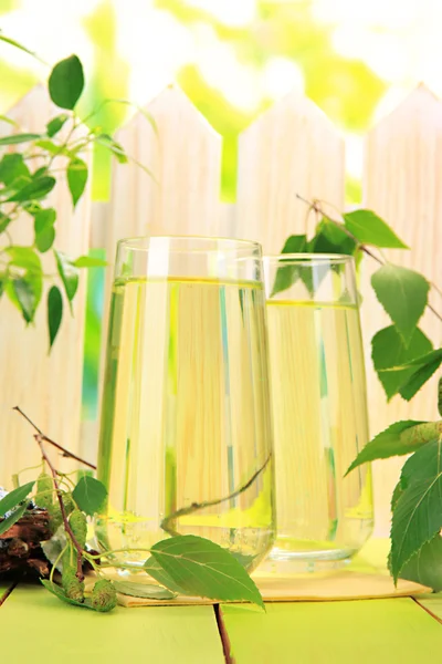 Lunettes de sève de bouleau sur table en bois vert — Photo