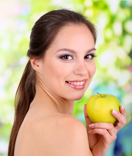 Mulher sorridente com maçã no fundo brilhante — Fotografia de Stock