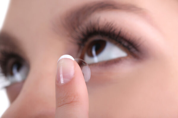Young woman putting contact lens in her eye close up