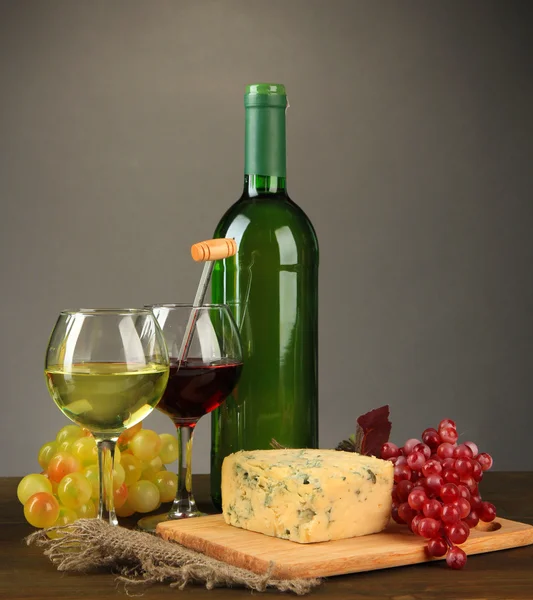 Σύνθεση με κρασιά, μπλε τυριά και σταφυλιών σε ξύλινο τραπέζι, σε γκρι φόντο — Φωτογραφία Αρχείου