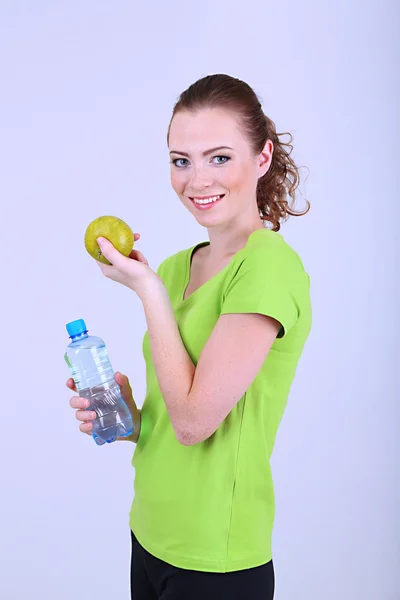Beautiful young woman with bottle of water and apple — Stock Photo, Image