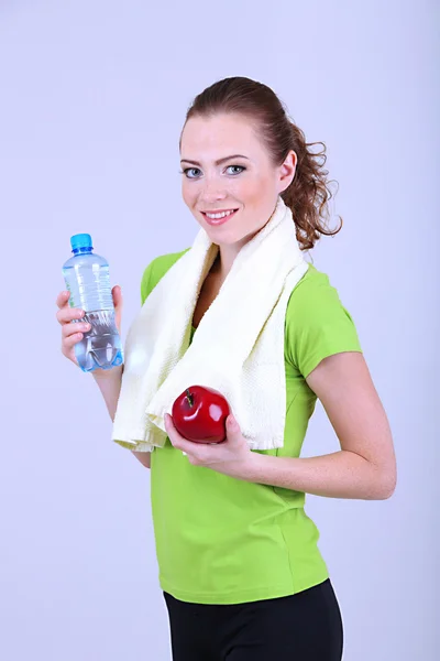 Beautiful young woman with bottle of water and apple — Stock Photo, Image