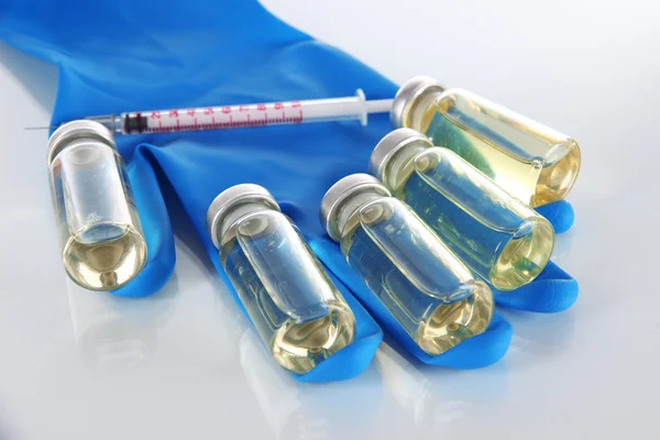 Medical bottles and syringe on hand on light gray tone — Stock Photo, Image