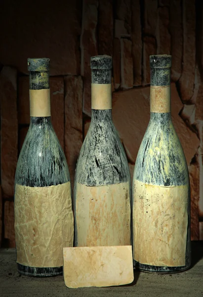 Old bottles of wine in old cellar, on dark background — Stock Photo, Image