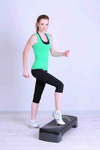 Beautiful young woman exercises on stepper — Stock Photo, Image