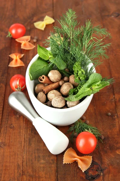 Herbes et épices en mortier céramique, sur fond bois — Photo