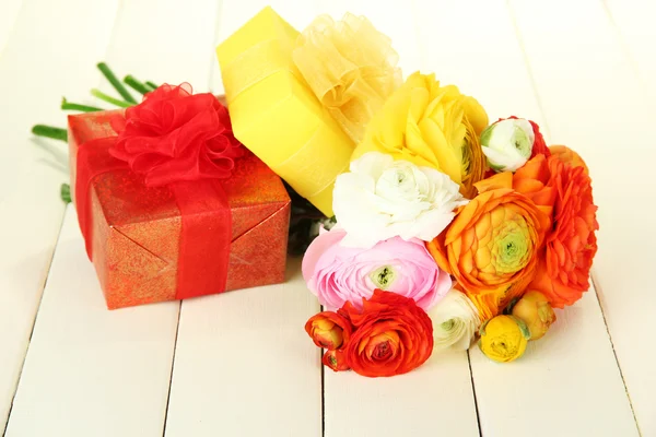 Ranunculus (Perzisch boterbloemen) en geschenken, op witte houten achtergrond — Stockfoto