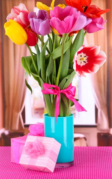 Mooie tulpen in boeket met geschenken op tafel op kamer — Stockfoto