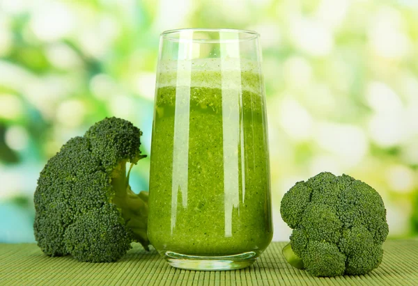 Glass of broccoli juice, on bamboo mat, on green background — Stock Photo, Image