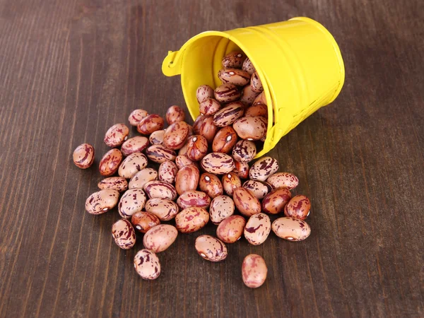 Overturned bucket with beans on wooden background — Stock Photo, Image