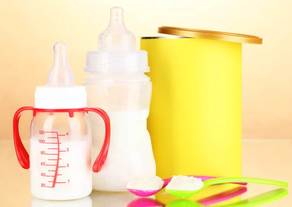 Bottles with milk and food for babies on beige background — Stock Photo, Image