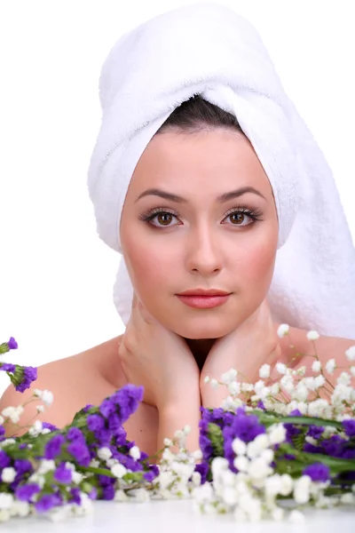 Schöne junge Frau mit Handtuch auf dem Kopf und Blumen isoliert auf weiß — Stockfoto