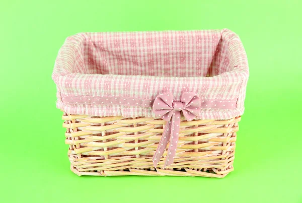 Wicket basket with pink fabric and bow, on color background — Stock Photo, Image