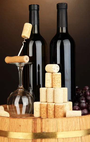 Wine and corks on barrel on brown background — Stock Photo, Image
