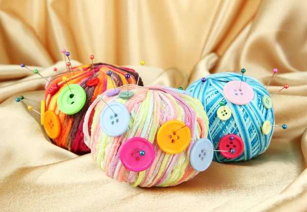 Colorful buttons and multicolor wool balls, on color fabric background — Stock Photo, Image