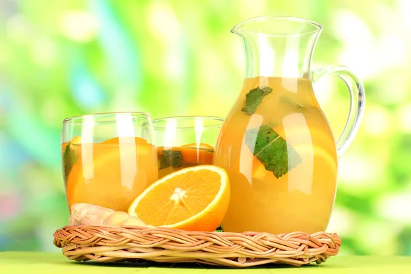 Pomarańczowy lemoniady w dzban i okulary na drewnianym stole na naturalne tło — Zdjęcie stockowe