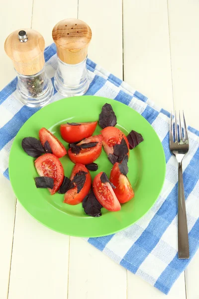 木製の背景にナプキンに新鮮なトマトとバジルのサラダの葉します。 — ストック写真