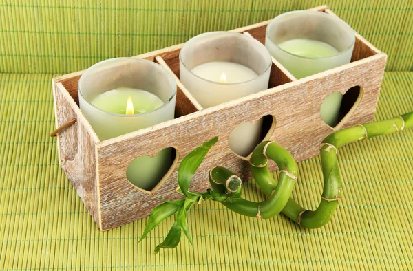 Candeliere in legno con candele e bambù, su tappetino verde — Foto Stock