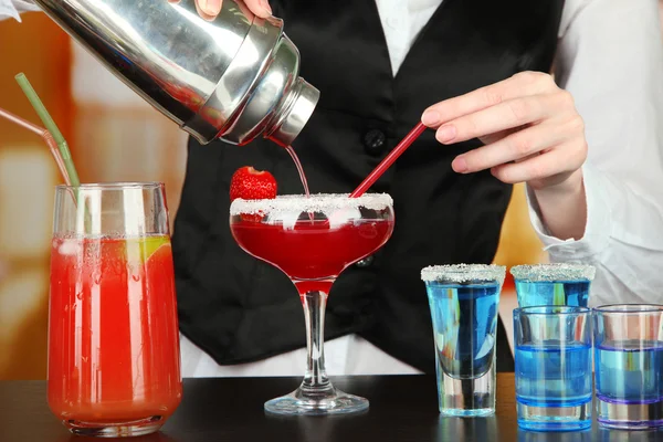 Barmen hand with shaker pouring cocktail into glass, on bright background — Stock Photo, Image