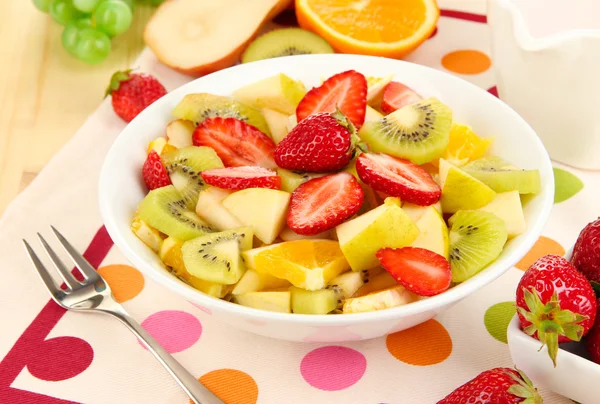 Χρήσιμο φρούτα σαλάτα από φρέσκα φρούτα και τα μούρα σε μπολ σε χαρτοπετσέτα σε κοντινό πλάνο ξύλινο τραπέζι — Φωτογραφία Αρχείου