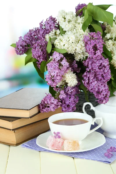 Samenstelling met prachtige lila bloemen, thee service op houten tafel op lichte achtergrond — Stockfoto