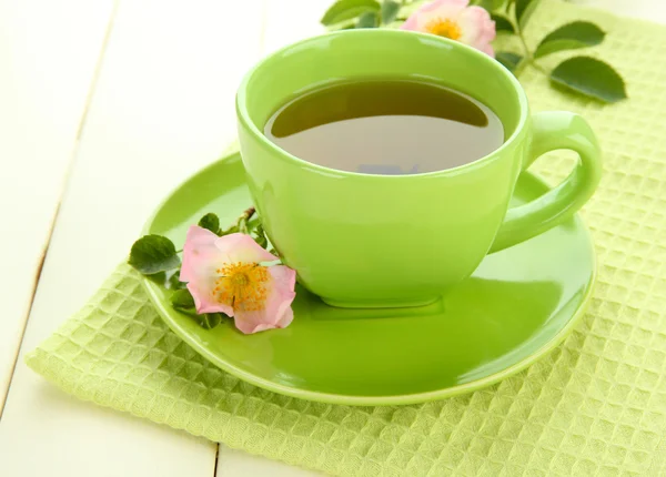 Xícara de chá de ervas com flores de rosa do quadril na mesa de madeira branca — Fotografia de Stock