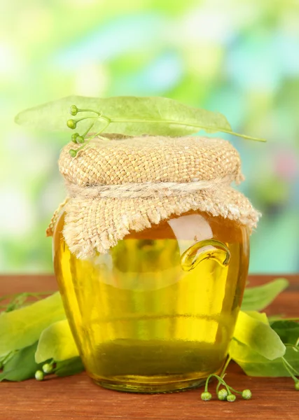 Jarro de mel com flores de visco, na mesa de madeira no fundo brilhante — Fotografia de Stock