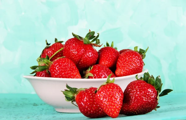 Erdbeeren im Teller auf blauem Hintergrund — Stockfoto