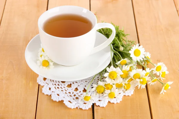 Cup of chamomile tea and chamomile on wooden table — Stock Photo, Image