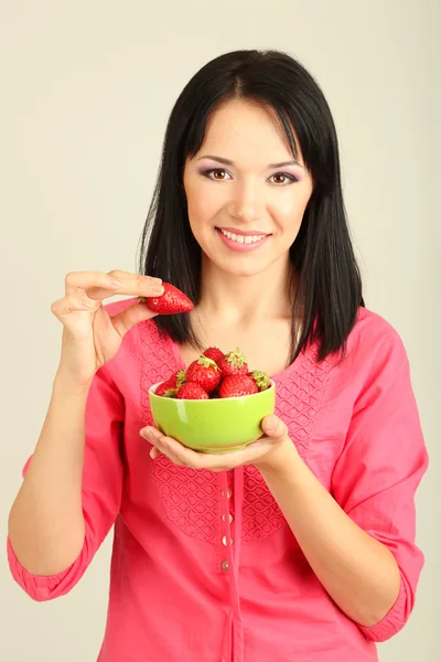 Hermosa joven con fresas sobre fondo gris — Foto de Stock