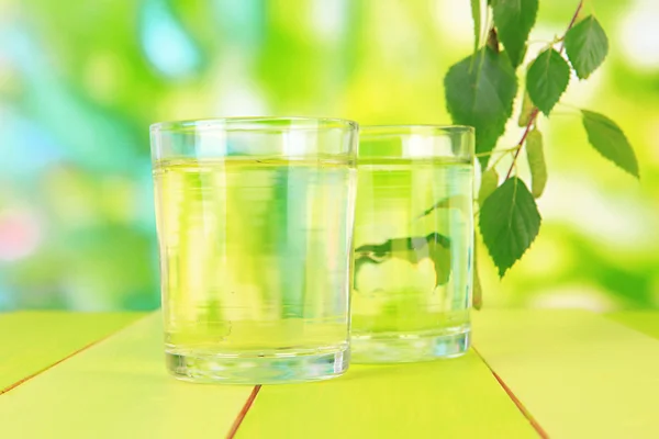 Окуляри березового соку на дерев'яному столі, на зеленому фоні — стокове фото