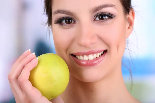 Mujer sonriente con manzana sobre fondo brillante — Foto de Stock