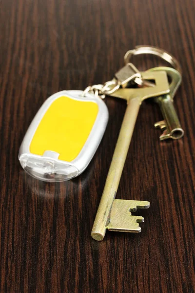 Ключі від будинку та брелок на дерев'яному фоні — стокове фото