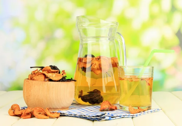 Assorted dried fruits in bowl and compote of dried fruits on wooden table on natural background — Stock Photo, Image