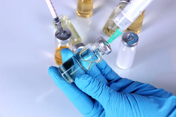 Medizinische Flaschen und Spritzen in der Hand auf grauem Hintergrund — Stockfoto