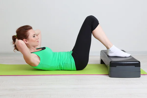 Beautiful young woman exercises on stepper — Stock Photo, Image