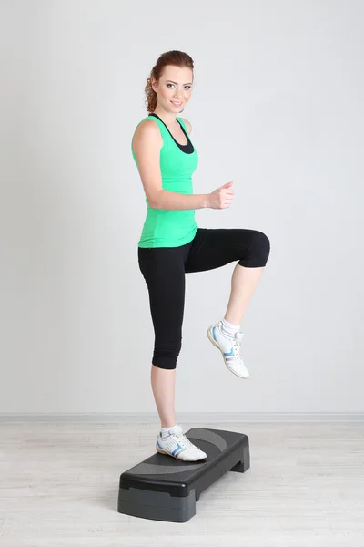 Beautiful young woman exercises on stepper — Stock Photo, Image