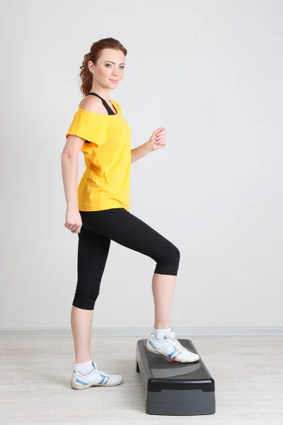 Beautiful young woman exercises on stepper — Stock Photo, Image