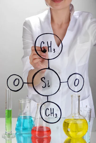 Chemikerin schreibt Formeln auf Glas auf grauem Hintergrund — Stockfoto