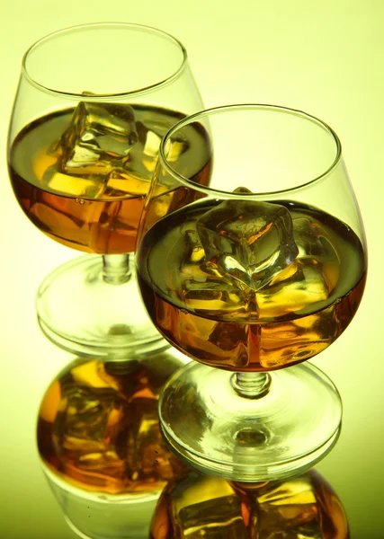 Copas de brandy con hielo sobre fondo verde —  Fotos de Stock