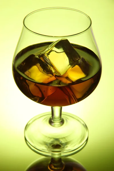 Bicchiere di brandy con ghiaccio su sfondo verde — Foto Stock