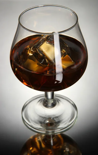 Bicchiere di brandy con ghiaccio su sfondo grigio — Foto Stock