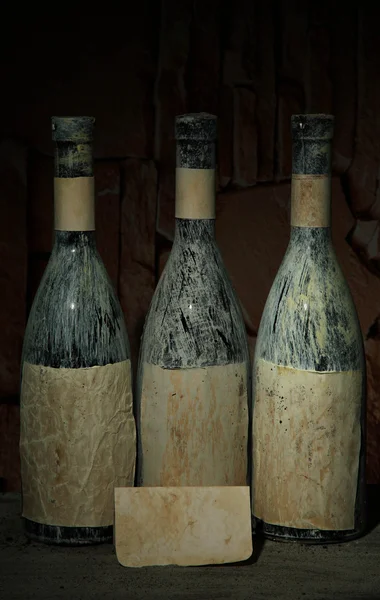 Vecchie bottiglie di vino in vecchia cantina, su sfondo scuro — Foto Stock