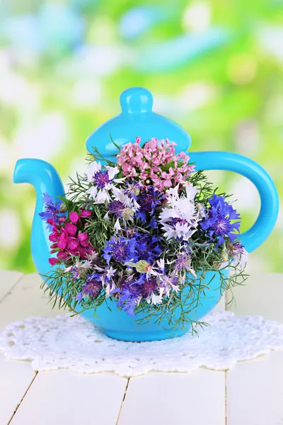 Beautiful bouquet in blue teapot on wooden table on natural background — Stock Photo, Image