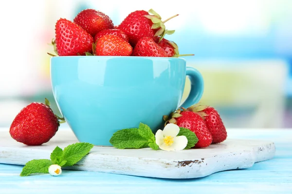 Ripe sweet strawberries in cup on blue wooden table — Stock Photo, Image