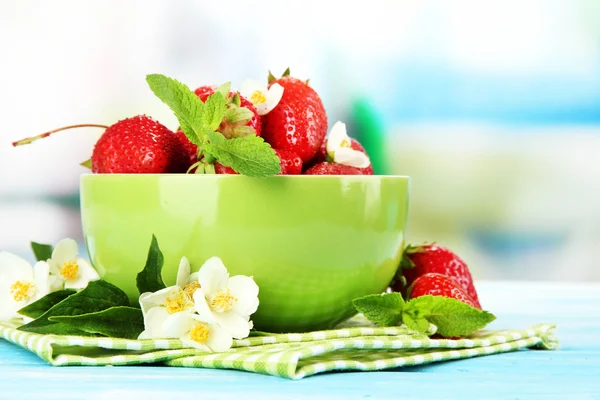 Zralé sladké jahody v zelené prohlubni na modré dřevěný stůl — Stock fotografie