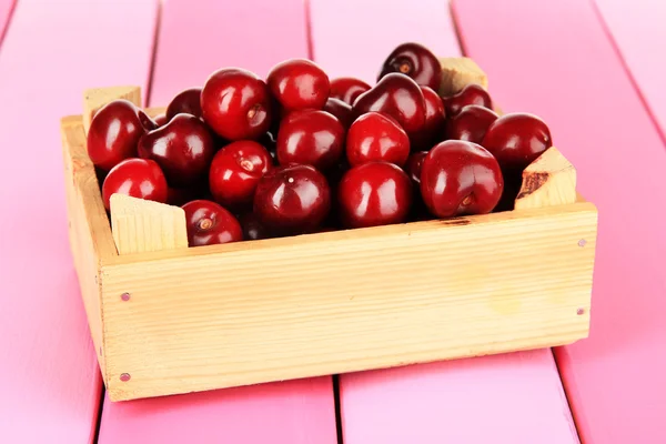 Kirschbeeren in Holzkiste auf Holztisch in Großaufnahme — Stockfoto